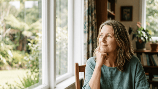 Woman around 50 by a window with tea, looking clear-headed and calm — menopause brain fog guide