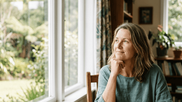 Woman around 50 by a window with tea, looking clear-headed and calm — menopause brain fog guide